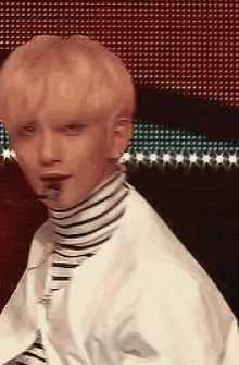 a close up of a young man wearing a striped turtleneck and a white shirt .