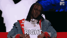 a man with dreadlocks is sitting on a red couch with the word right written on his chest