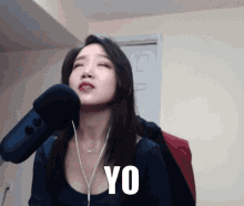 a woman singing into a microphone with yo written on the bottom of her face