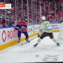 a hockey game is being played in front of a large rogers advertisement
