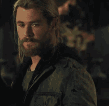 a close up of a man with a beard wearing a black jacket and a black shirt .