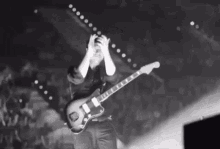 a man is holding his head while playing a guitar on stage .