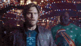 a man in a christmas sweater stands next to a man in a leather jacket