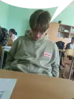 a boy in a nasa hoodie sits at a desk in a classroom