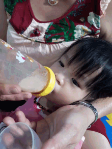 a baby drinking from a bottle with an elephant on the cap