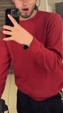 a man in a red shirt is taking a picture of himself