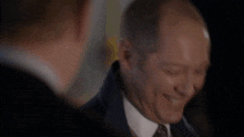 a man in a suit and tie with his eyes closed smiles