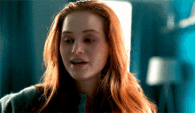 a close up of a woman 's face with red hair and a blue background .
