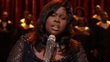 a woman singing into a microphone with her eyes closed and her hand up