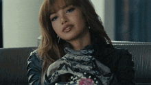 a woman sitting on a couch with a snakeskin scarf around her neck