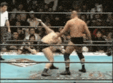 two men are wrestling in a ring with a referee watching .