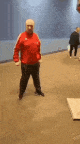 a man wearing a red jacket and a white hat is standing on a tiled floor .