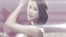 a woman without a shirt is smiling and holding her arm up