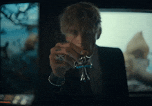 a man in a suit is holding a cross in his hand in front of a television .