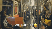 a group of people are sitting on a subway train and the words `` we did it '' are written on the screen .