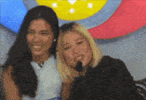 two women are posing for a picture in front of a microphone and smiling for the camera