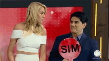 a man and a woman are standing next to each other with a sign that says sim