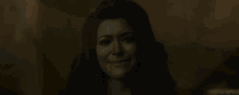 a woman with a green face is smiling in a dark room