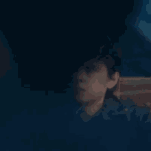 a close up of a man 's face in a dark room with a blurred background .