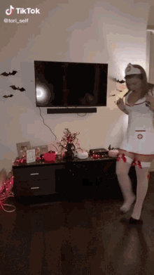 a woman dressed as a nurse is dancing in front of a tv