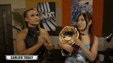 two women standing next to each other in front of a sign that says nxt