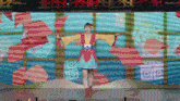 a woman in a yellow and red outfit is standing in front of a screen that says ' o ' on it