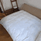 a bed with a white comforter on it in a bedroom