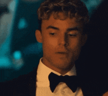 a man in a tuxedo and bow tie is looking down