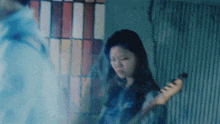 a woman is playing a guitar in front of a window in a dark room .