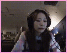 a woman wearing headphones looks at the camera with a pink frame around her