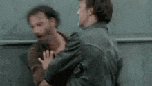 two men are standing next to each other and fighting .