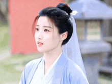 a woman wearing a blue kimono and a white veil has a flower in her hair ..