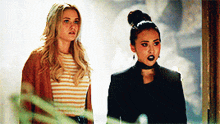 two women are standing next to each other and one has a choker around her neck .