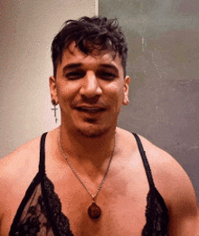 a shirtless man wearing a bra and a necklace