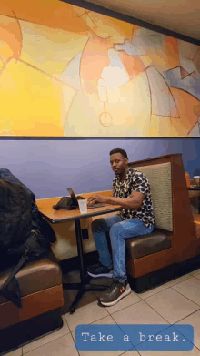 a man sits in a booth at a table with the words take a break written below him