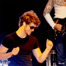 a man wearing sunglasses and a black shirt is dancing in front of a rbd gif