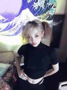 a woman in a black top stands in front of a painting of waves
