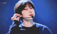 a young man wearing a microphone on his ear is looking at the camera .