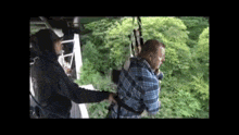 a man in a plaid shirt is being helped by a woman in a hoodie