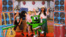a group of people are dancing with a green gummy bear