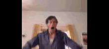 a man is standing in a room with his arms outstretched and his mouth open .