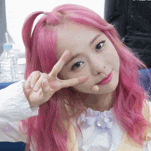 a girl with pink hair giving the peace sign