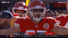 a football player wearing a red helmet stands in front of a crowd
