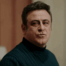a man in a turtleneck sweater looks at the camera