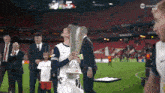 a man holding a trophy on a soccer field with tnt sports on the bottom right