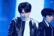 a man in a leather jacket stands next to another man with a microphone in his mouth ..