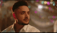 a man with a beard wearing a white shirt looks at something