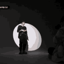 a man in a black jacket is standing in front of a white circle with a yellow sticker that says ' a '