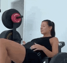 a pregnant woman is doing squats on a machine with a barbell .