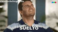a man in a blue and white striped shirt is laughing with the word suelto behind him